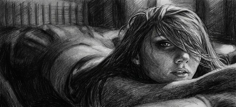 Un dessin au crayon noir détaillé et texturé d'une jeune femme allongée sur le ventre, appuyée sur ses avant-bras. Elle regarde fixement et intensément vers l'avant, avec un œil visible à travers ses cheveux longs et désordonnés qui couvrent partiellement son visage. Son corps s'étend vers un arrière-plan sombre et flou, s'estompant dans l'ombre texturée. L'ambiance est intime et intense.